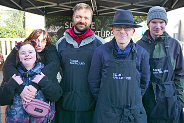 Gruppenbild vom Verkaufsteam vor dem Marktstand, 