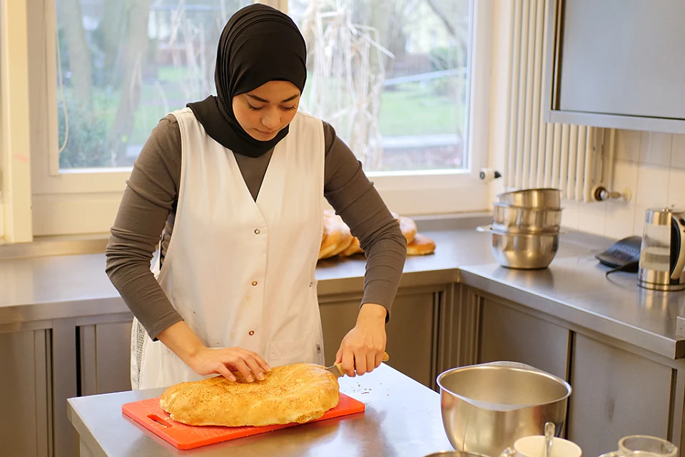 Eine weibliche Person schneidet Fladenbrot auf.