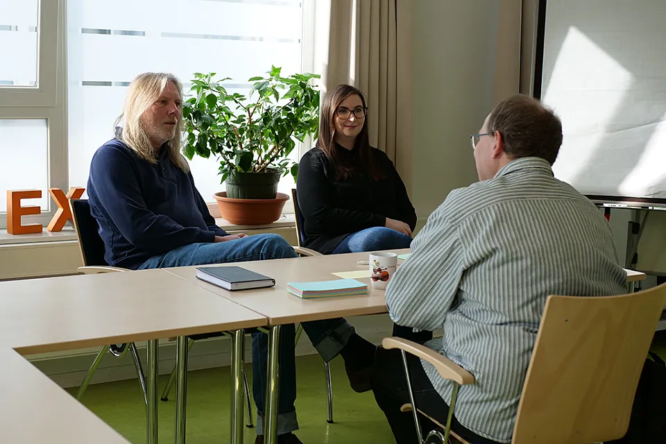 3 Teammitglieder am Tisch im Gespr&auml;ch