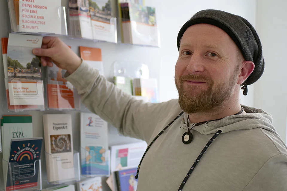 Ein Teammitglied nimmt einen Flyer aus einem Wandregal.