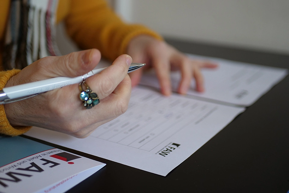 Berantende f&uuml;llt ein Formular aus. Nahaufnahme Hand mit Kugelschreiber und Formular