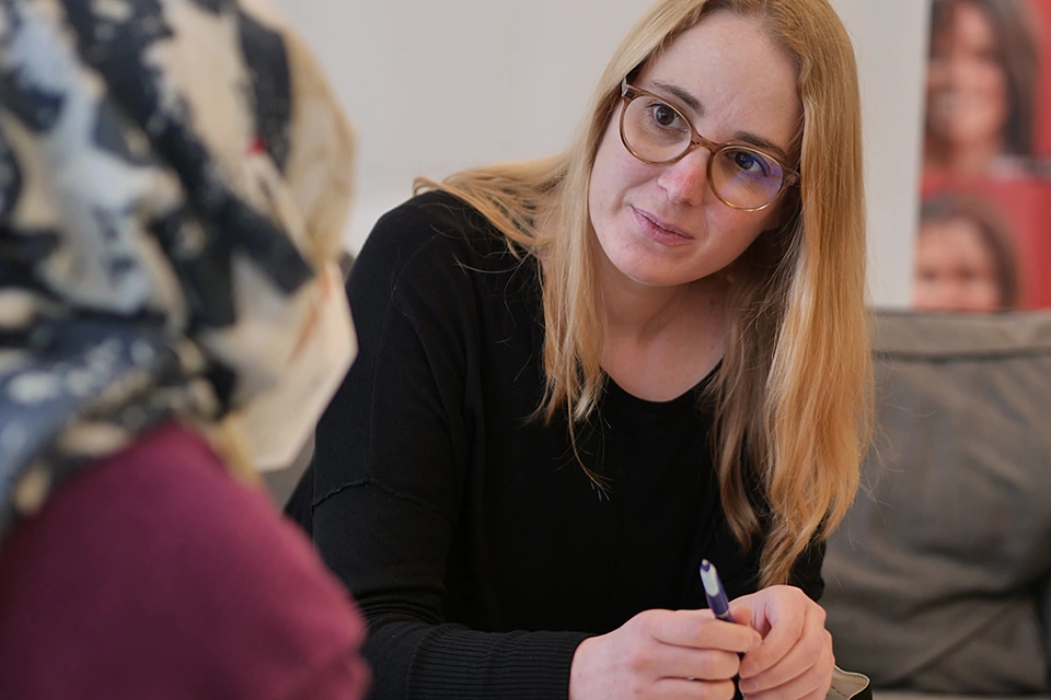 Berater*in in einem Gespr&auml;ch mit einer weiblichen Person mit Migrationshintergrund.