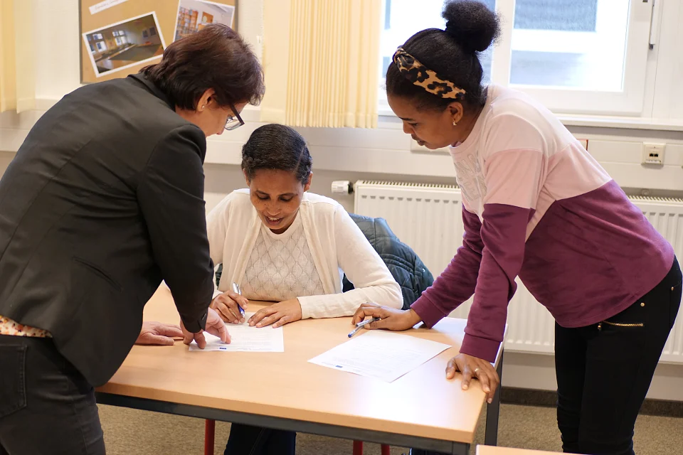 Teilnehmerinnen und eine Beraterin f&uuml;llen gemeinsam Formulare aus