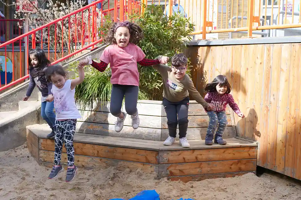 Kinder h&uuml;pfen gemeinsam von einer kleinen Mauer