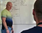 Coach steht vor dem Whiteboard 
˜ Bildnachweis: eventfive GmbH, Indra Zilm