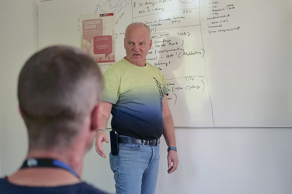 Coach erkl&auml;rt etwas. Im Vordergrund Teilnehmenden von der R&uuml;ckansicht.