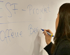 Eine Frau schreibt offene Bratung an ein Whiteboard 
˜ Bildnachweis: eventfive GmbH, Indra Zilm