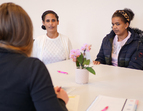 Drei Personen an einem Tisch. Zwei Teilnehmerinnen im Gespräch mit einer Beraterin 
˜ Bildnachweis: eventfive GmbH, Indra Zilm