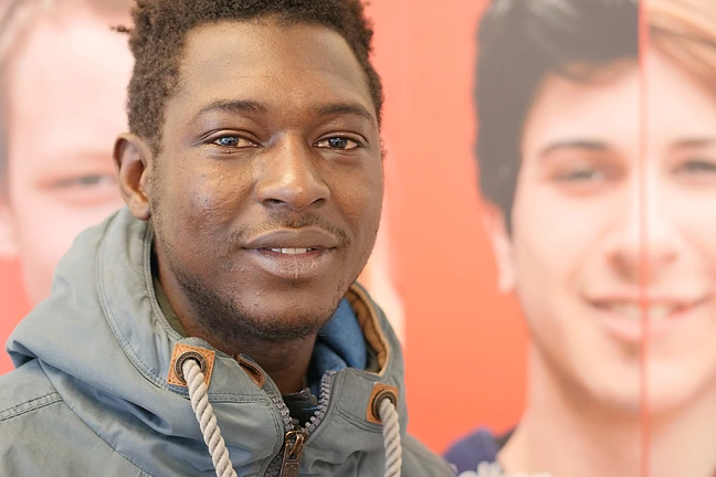 Person mit Mgrationshintergrund vor einer Fotowand