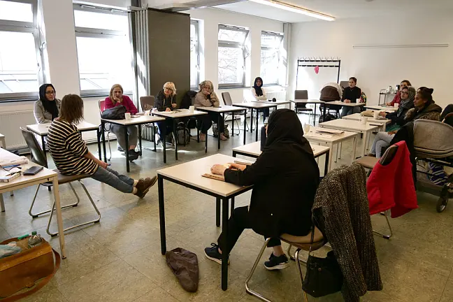 Frauen sitzen an Schultischen