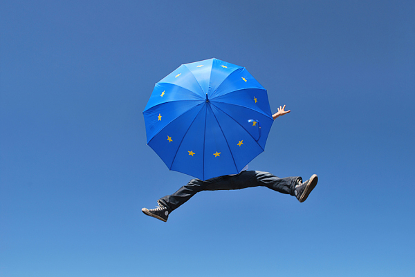 Person springt mit EU-Regenschirm in die Luft.