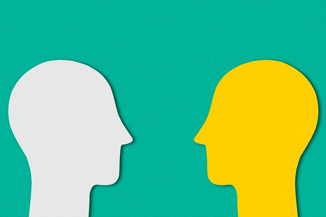 Zwei zugewandte Köpfe aus Papier ausgeschnitten.