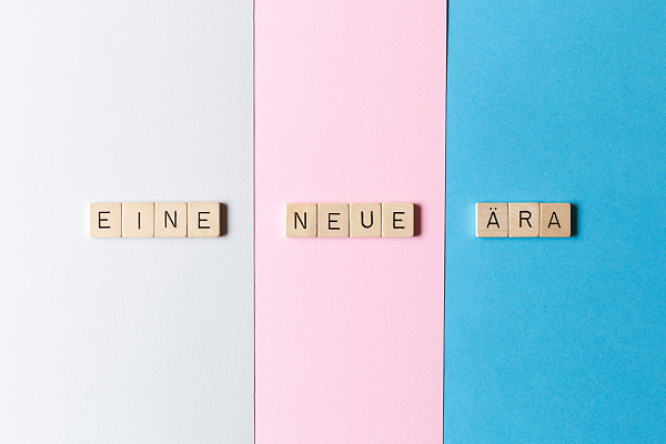 Scrabble Buchstaben auf dreifarbigen Untergrund bilden die Wörter Eine neue Ära