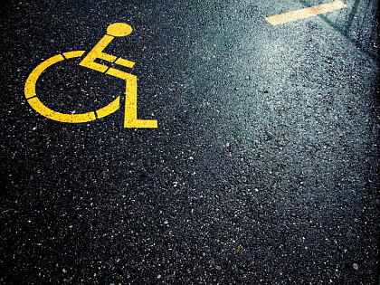 Gelber Rollstuhl gemalt auf schwarzen Asphalt