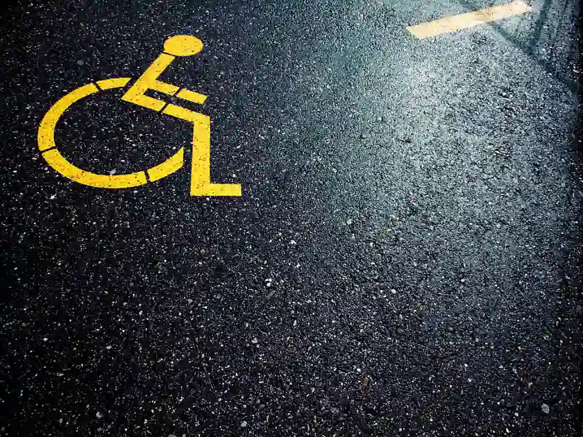 Gelber Rollstuhl gemalt auf schwarzen Asphalt